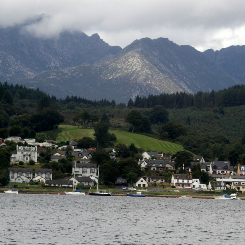 Scenic photograph of Arran with hills, coastal housing and sea