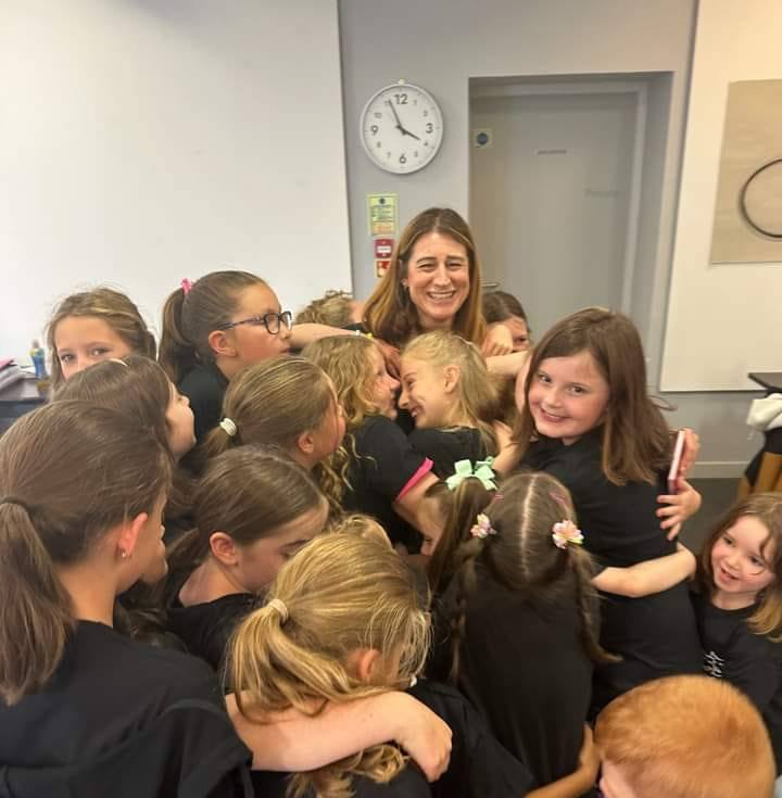 Drama group leader receiving group hug from young performers