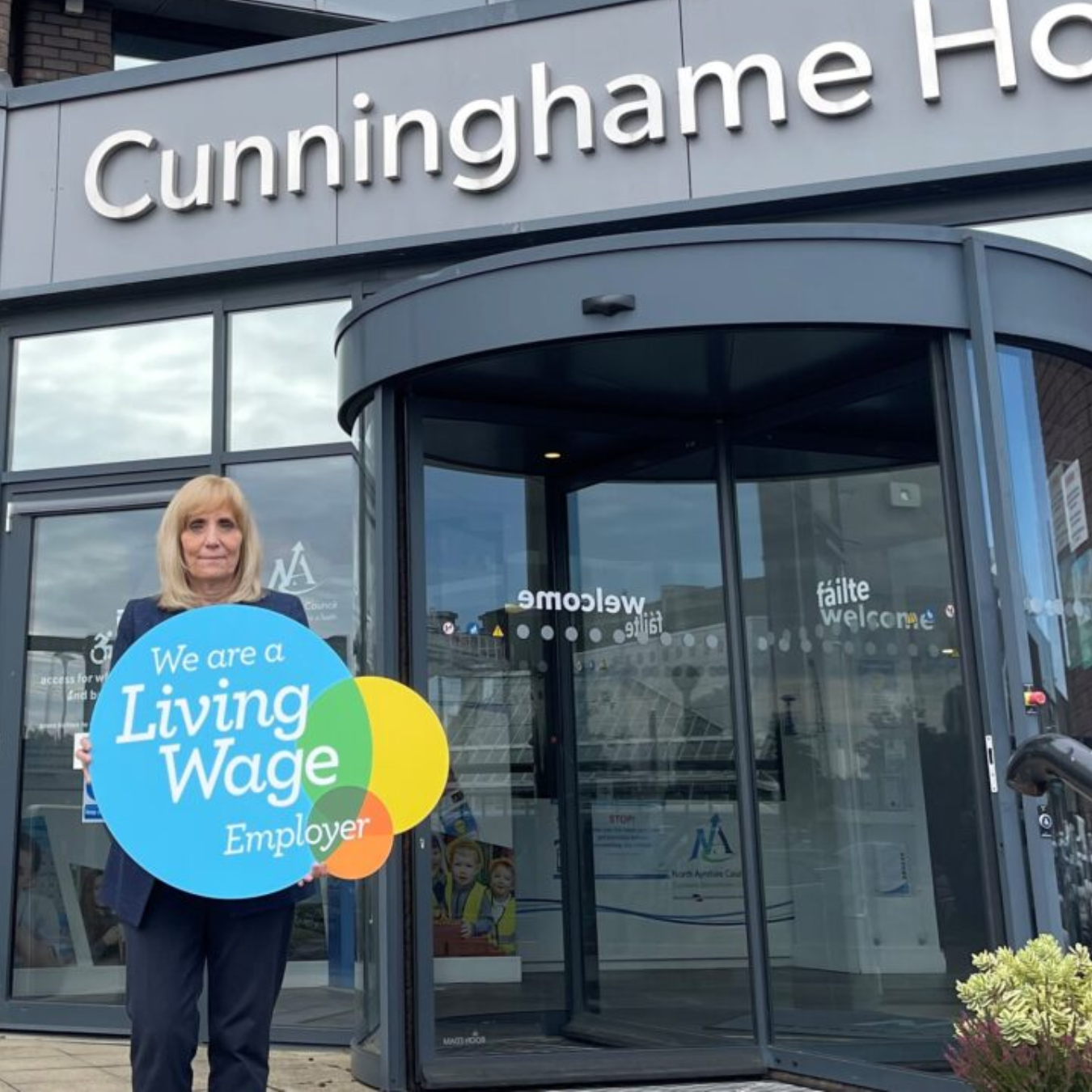 Council Leader with Living Wage Employer sign outside of Council HQ
