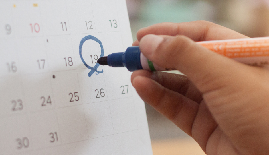 An image showing someone using a pen to circle a date in a calendar