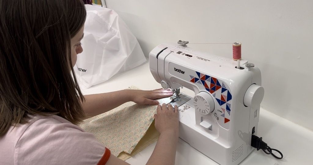 Resident uses sewing machines at Lend and Mend hub Kilbirnie Library
