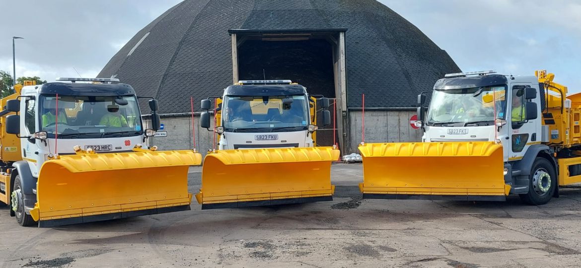 A picture showing a fleet on gritters in front of a grit storage shed