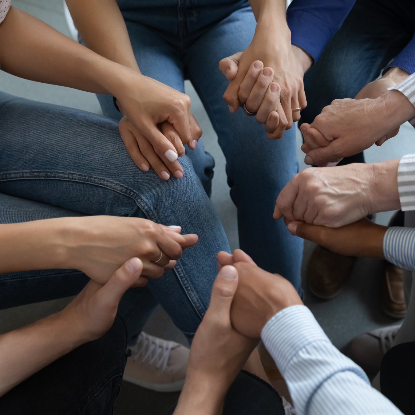 Close up of seated group holding hands in a circle at support session