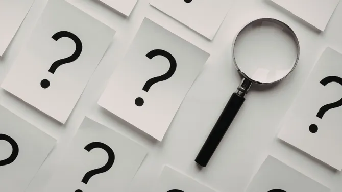 Magnifying glass with lots of sheets of A4 paper with question marks