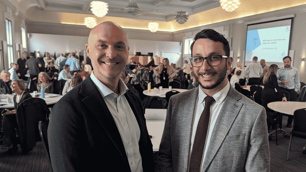 Two men standing smiling in a crowded hall